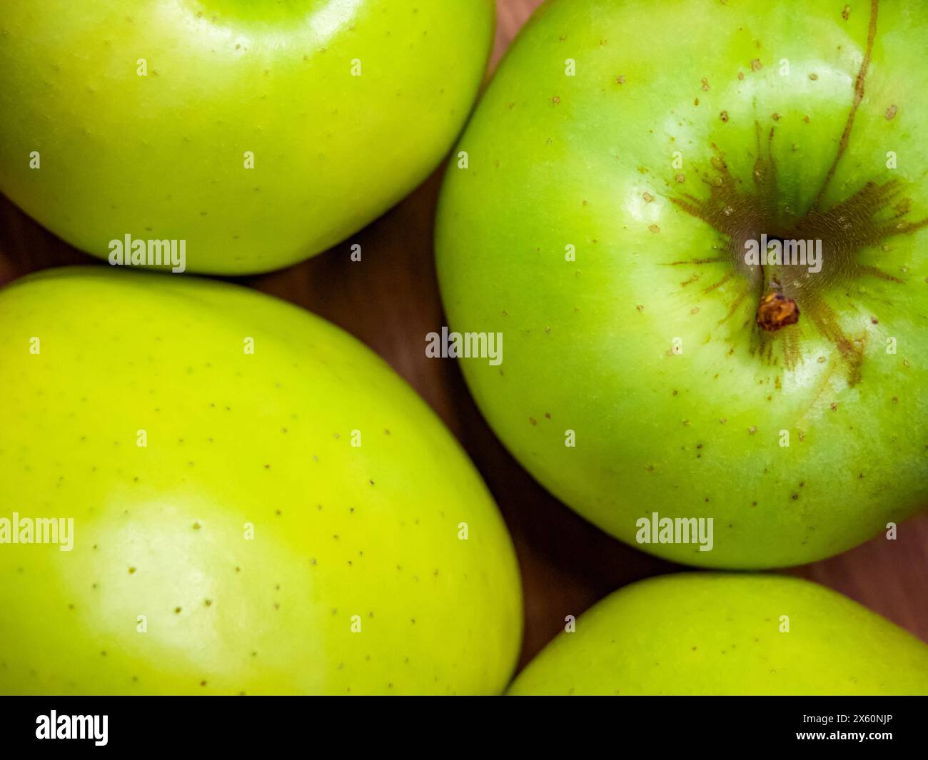 Grüne Äpfel mit frischem Glanz, einige mit braunen Flecken, auf neutralem Hintergrund. Stockfoto