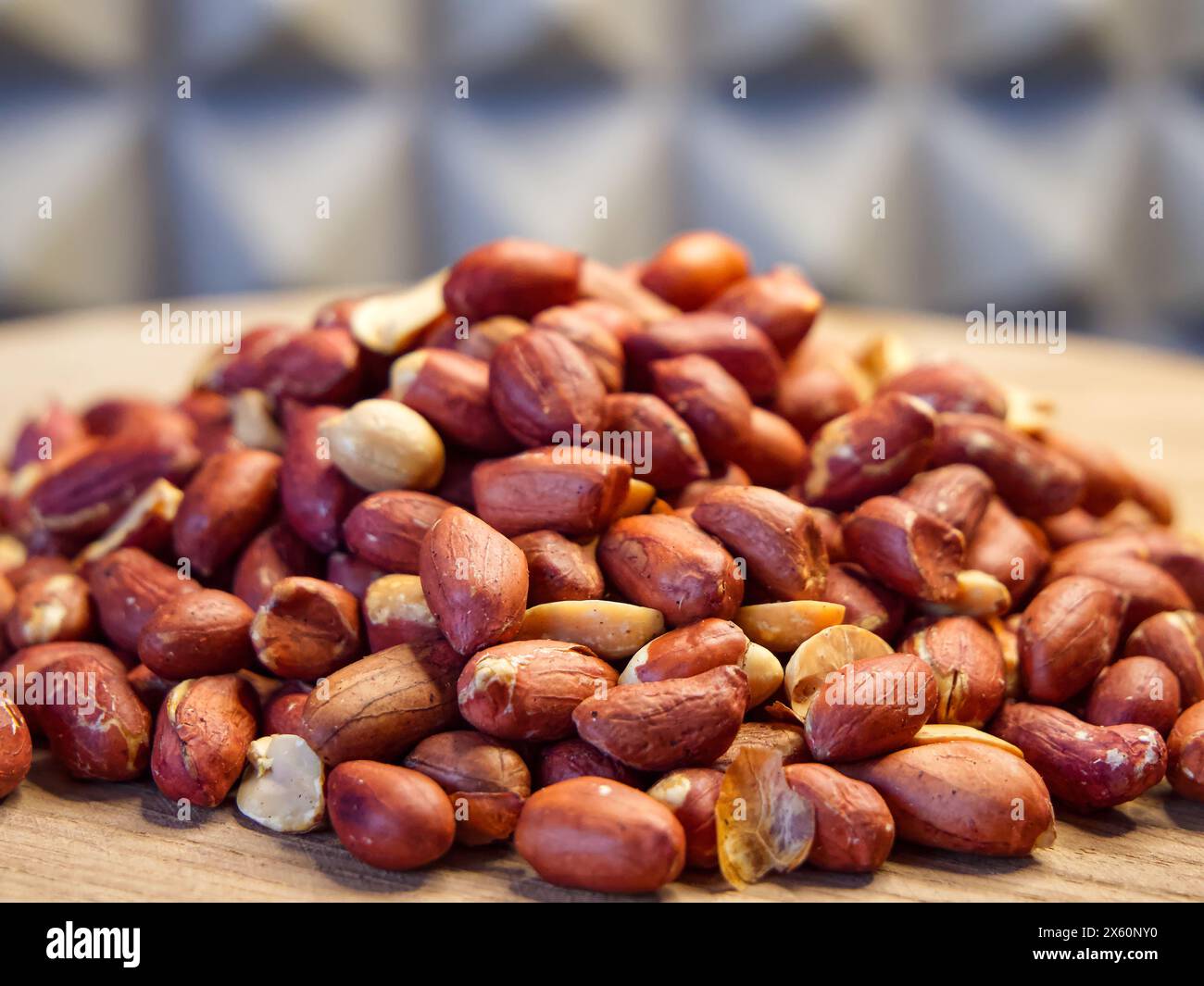 Erdnüsse auf Holz. Erdnüsse mit Schale, verstreut auf einer Holzoberfläche, ideal für Lebensmittel- und Ernährungsthemen. Stockfoto