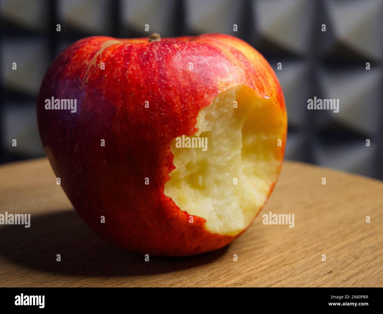 Gebissener Apfel auf Holz. Ein roter Apfel mit herausgenommenem Biss, auf eine Holzoberfläche gelegt, vermittelt Frische und Gesundheit. Stockfoto