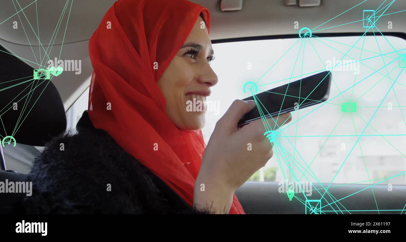 Bild von verbundenen Ikonen Globen über einer kaukasischen Frau, die Hijab mit dem Sprachassistenten im Auto trägt Stockfoto