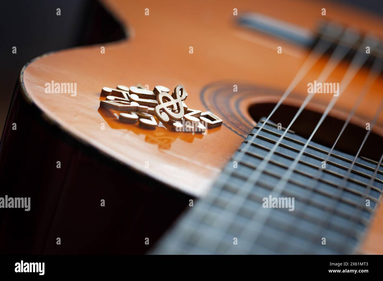 Ein Haufen hölzerner Musiknoten auf dem Soundboard einer klassischen Gitarre, Nahaufnahme. Das Konzept des Komponierens und Aufführens von Musik Stockfoto
