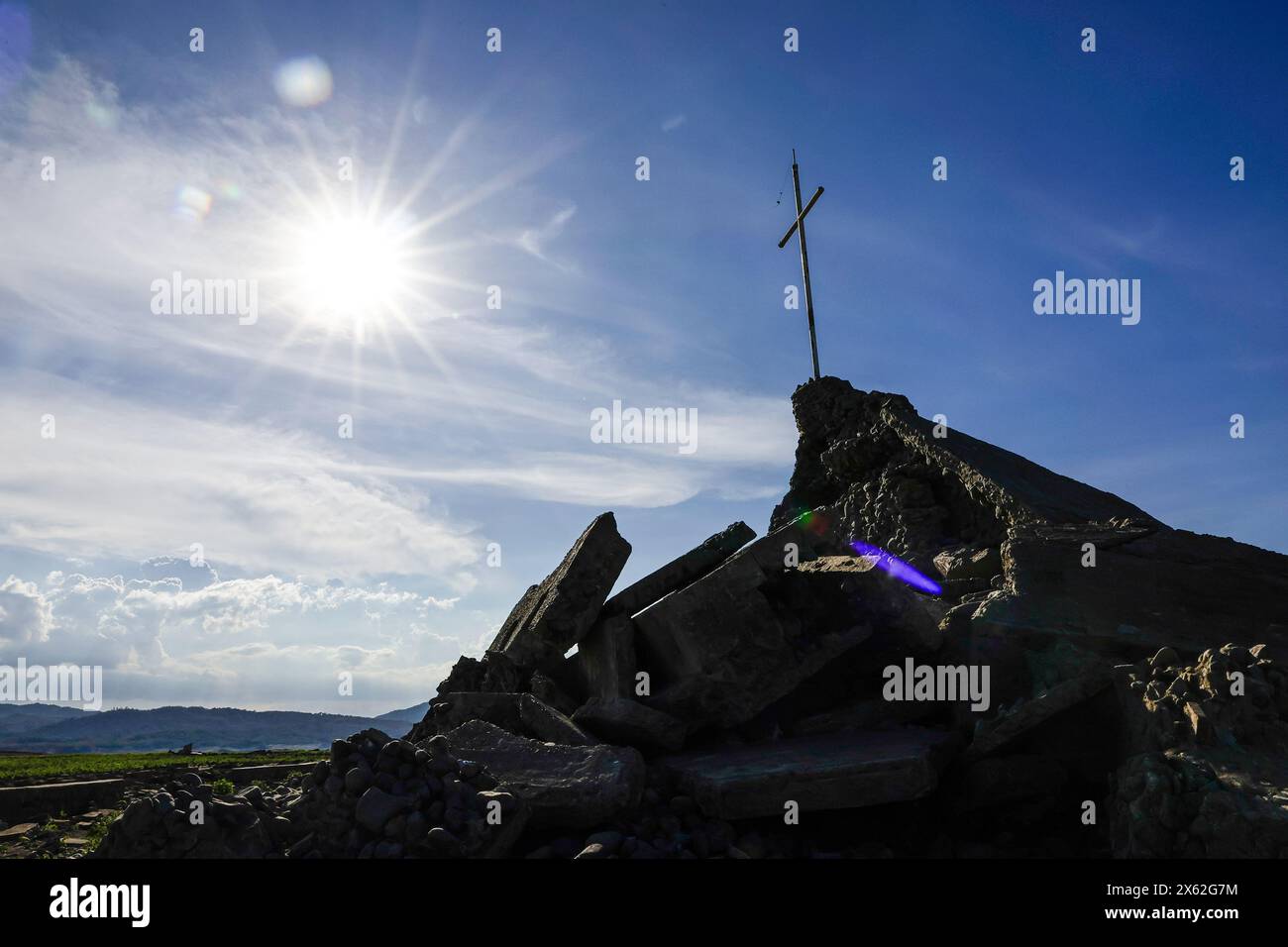 Pantabangan, Philippinen. 12. Mai 2024, Pantabangan, Philippinen: Reste der alten versunkenen Stadt Pantabangan, die wieder aufgetaucht sind, werden durch einen verwelkten Baum an einem trockenen Teil des Reservoirs gesehen, als Folge einer schweren Dürre aufgrund der steigenden Temperaturen auf den Philippinen. Das sechste Wiederauftauchen dieser 300 Jahre alten Siedlung, die eine Kirche und mehrere Grabsteine umfasst, hat Touristen zu Besuch gezogen, nachdem der Wasserstand am Damm aufgrund der El Nino Klimabildungen gesunken ist. Quelle: ZUMA Press, Inc./Alamy Live News Stockfoto