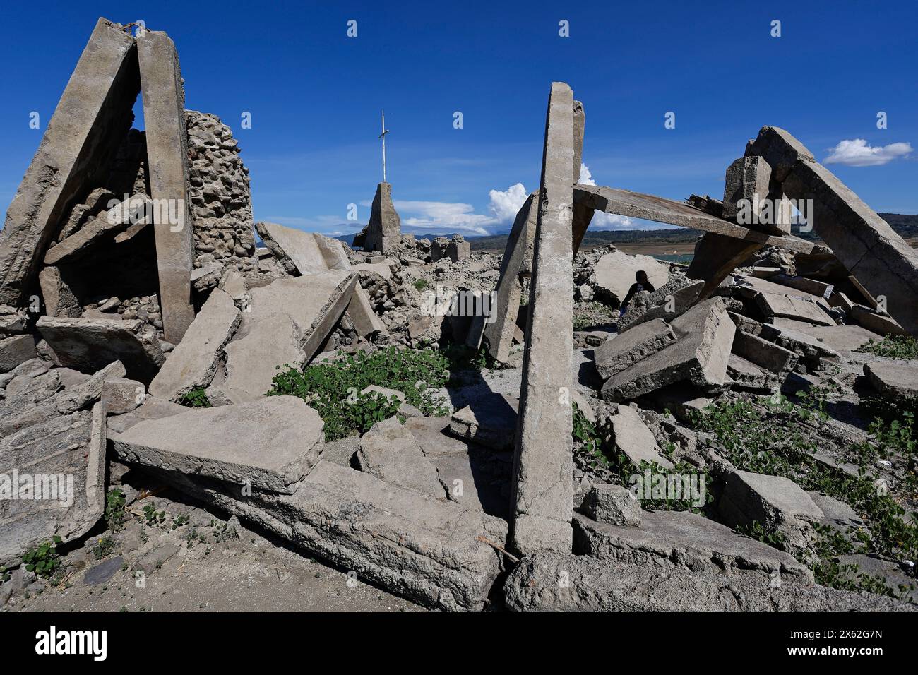 Pantabangan, Philippinen. 12. Mai 2024, Pantabangan, Philippinen: Reste der alten versunkenen Stadt Pantabangan, die wieder aufgetaucht sind, werden durch einen verwelkten Baum an einem trockenen Teil des Reservoirs gesehen, als Folge einer schweren Dürre aufgrund der steigenden Temperaturen auf den Philippinen. Das sechste Wiederauftauchen dieser 300 Jahre alten Siedlung, die eine Kirche und mehrere Grabsteine umfasst, hat Touristen zu Besuch gezogen, nachdem der Wasserstand am Damm aufgrund der El Nino Klimabildungen gesunken ist. Quelle: ZUMA Press, Inc./Alamy Live News Stockfoto