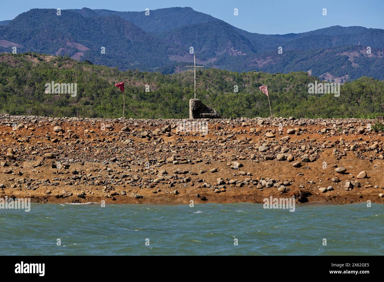 Pantabangan, Philippinen. 12. Mai 2024, Pantabangan, Philippinen: Reste der alten versunkenen Stadt Pantabangan, die wieder aufgetaucht sind, werden durch einen verwelkten Baum an einem trockenen Teil des Reservoirs gesehen, als Folge einer schweren Dürre aufgrund der steigenden Temperaturen auf den Philippinen. Das sechste Wiederauftauchen dieser 300 Jahre alten Siedlung, die eine Kirche und mehrere Grabsteine umfasst, hat Touristen zu Besuch gezogen, nachdem der Wasserstand am Damm aufgrund der El Nino Klimabildungen gesunken ist. Quelle: ZUMA Press, Inc./Alamy Live News Stockfoto