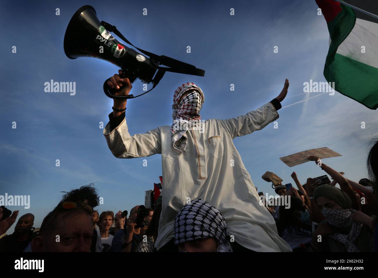 Ein Demonstrant mit einem Keffiyeh, der sein Gesicht bedeckt, hält ein Megaphon. In der Londoner Waterloo-Gegend wurde ein propalästinensischer Protest abgehalten, bei dem Demonstranten die Waterloo Bridge für eine gewisse Zeit geschlossen hatten. Die Demonstration wurde von der Youth Demand organisiert und von Gesundheitspersonal für Palästina unterstützt. Sie fordern ein Waffenembargo mit Israel und die Einstellung der Bombardierung Rafahs. Israel verfolgt den Gazastreifen über sechs Monate seit Kriegsbeginn weiter. Stockfoto