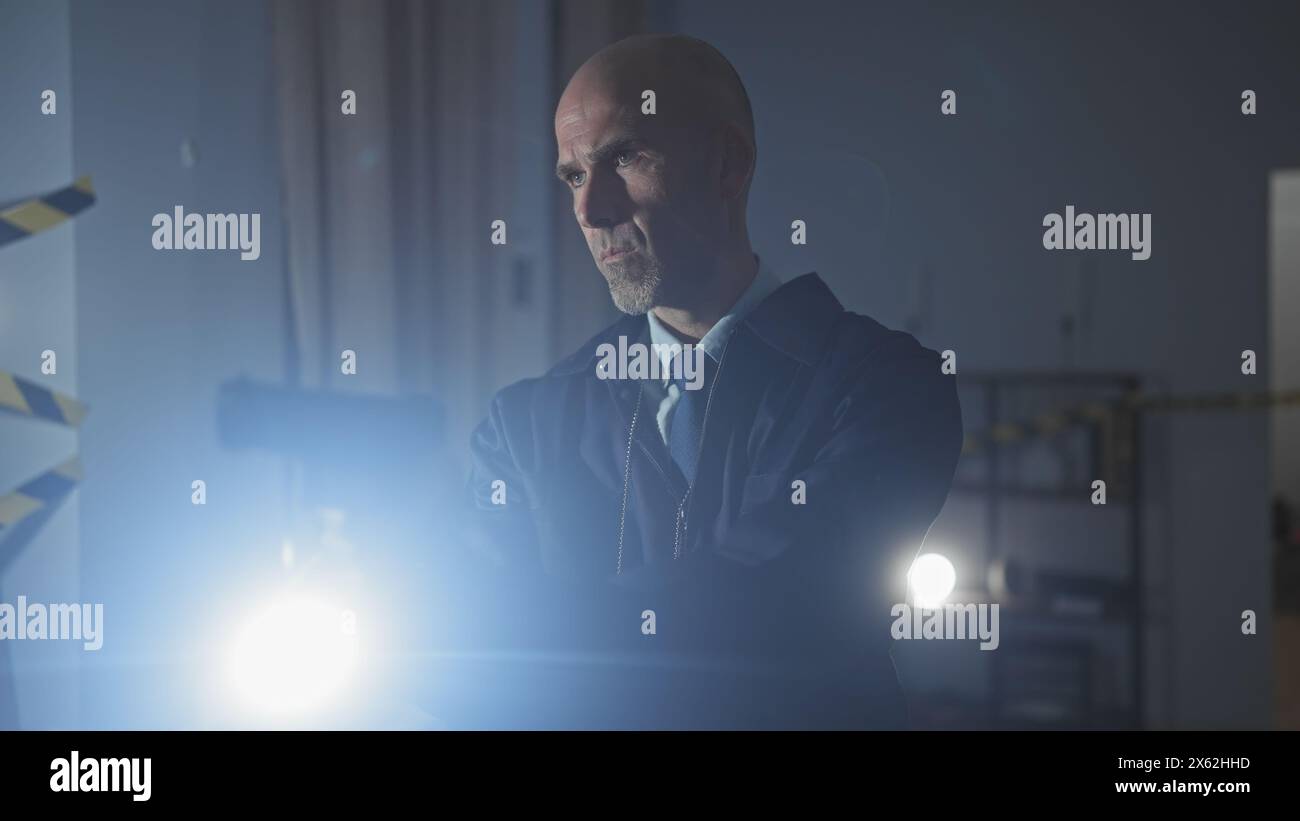 Intensiver kahlköpfiger Mann in Anzug drinnen, beleuchtet von hellem Licht und schafft eine dramatische geheimnisvolle Umgebung. Stockfoto