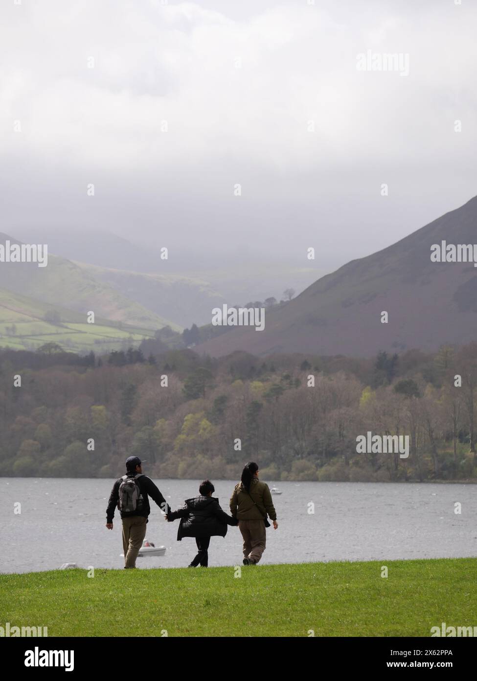 Junge Familie, die Hände hält und am See entlang spaziert. Derwentwater, Lake District, Cumbria, Großbritannien Stockfoto