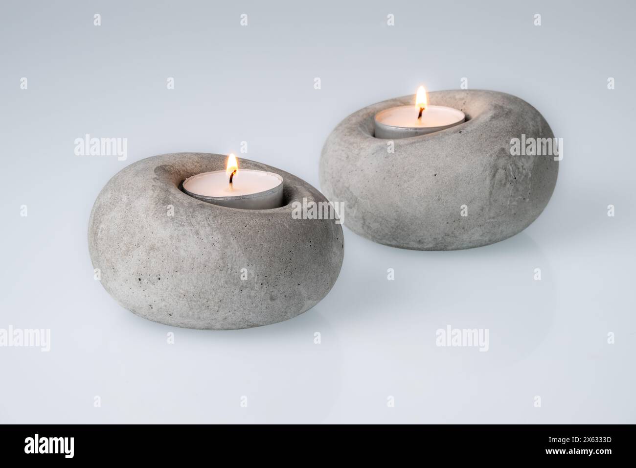 Teelichter brennen in Betonkerzenständern Stockfoto