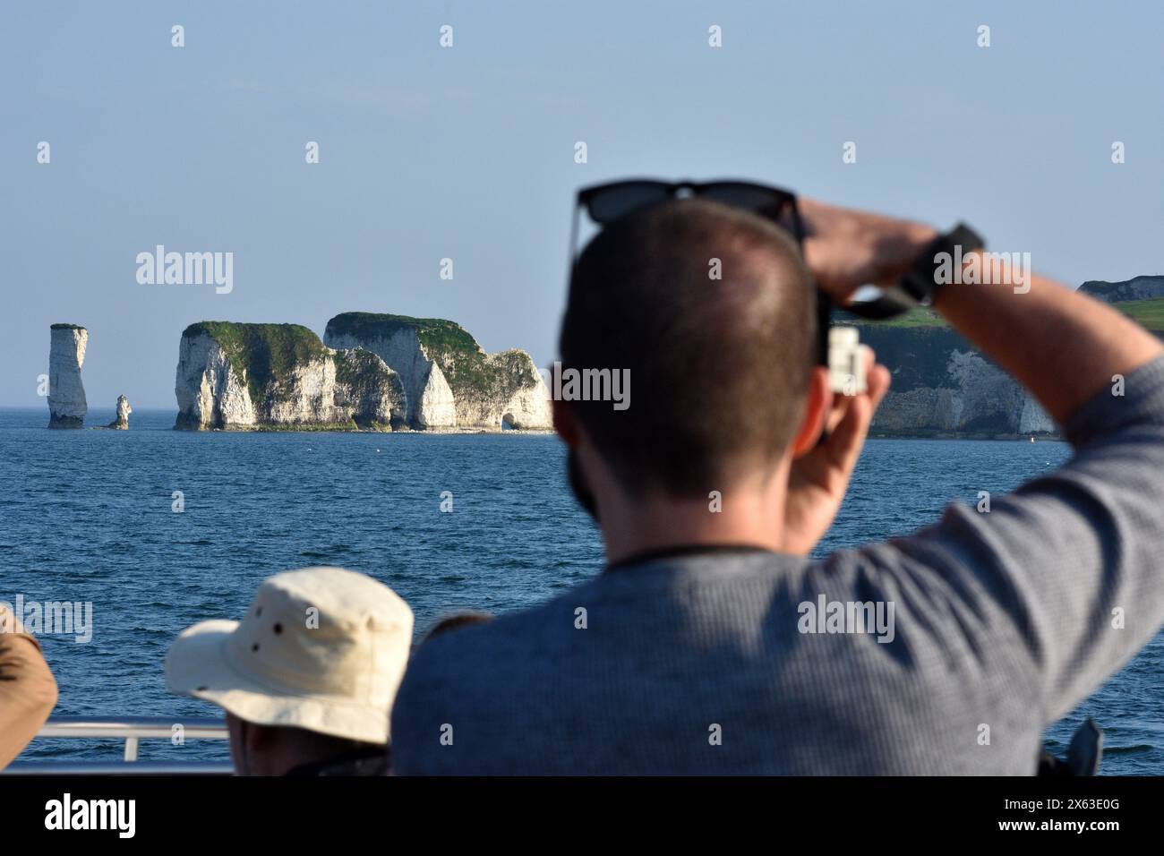Fotograf mit Sonnenbrille auf dem Kopf, der ein Bild von Old Harry Rocks an der Jurassic Coast komponiert. Dorset, Südengland, Großbritannien Stockfoto