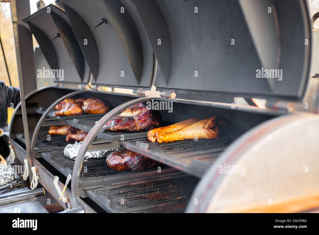 Putenschenkel und Lammfilet werden auf einem professionellen Grill gebacken. Der Prozess der Fleischzubereitung für ein Picknick. Stockfoto