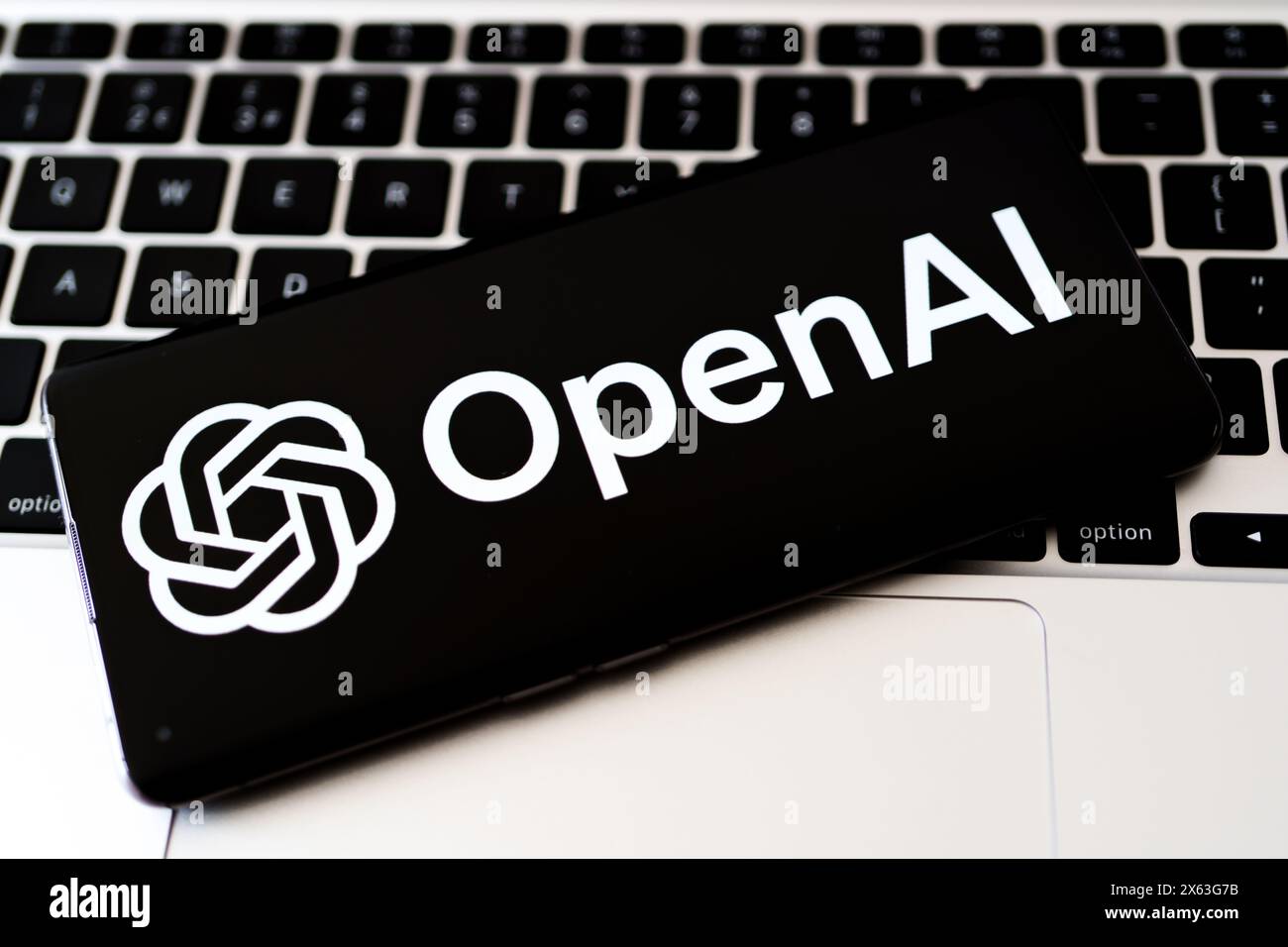 Smartphone mit OpenAI-Logo auf der MacBook-Tastatur. Symbol für modernste KI-Technologie. Stafford, Vereinigtes Königreich, 28. April 2024 Stockfoto