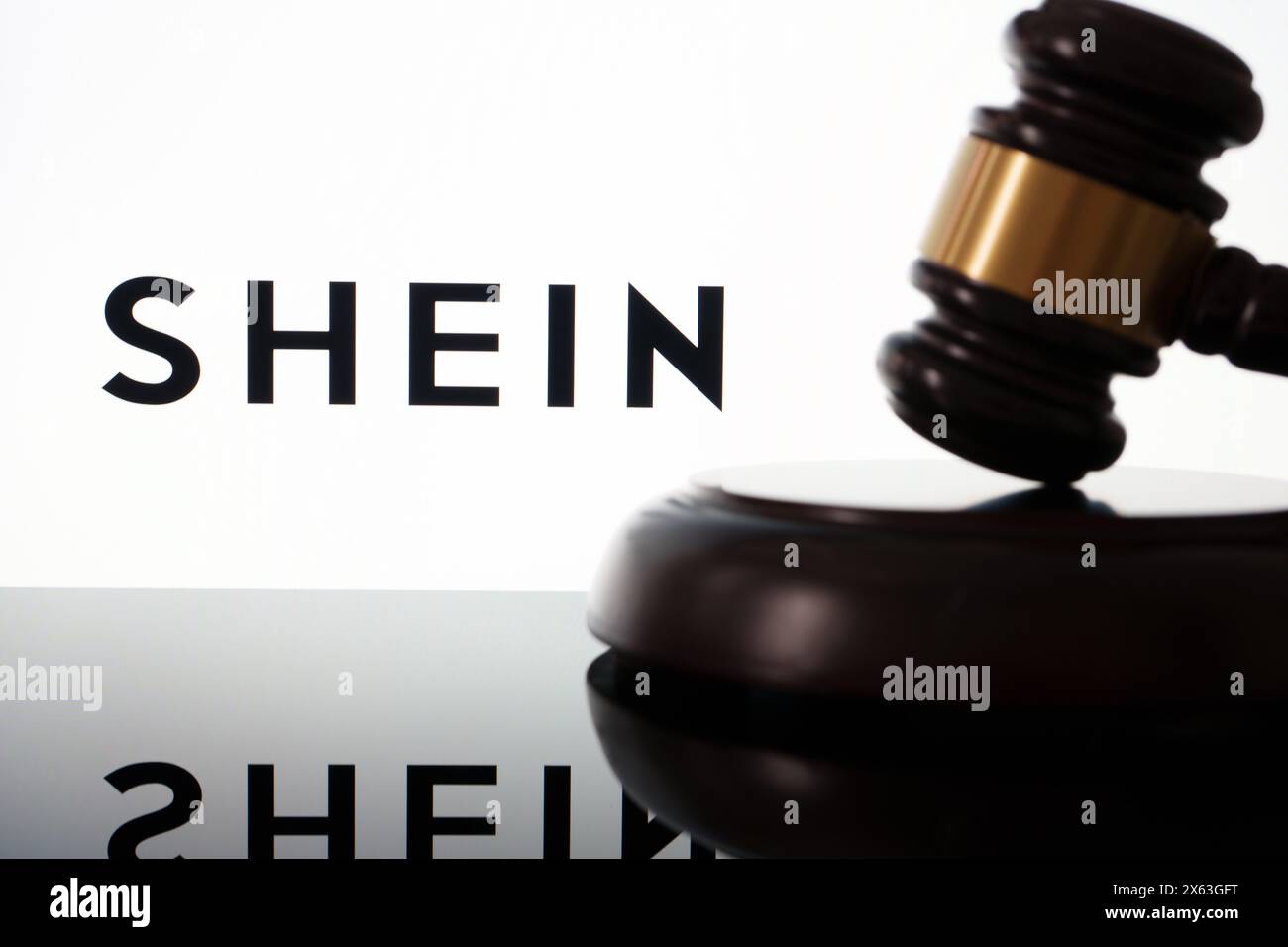 Das SHEIN Logo auf dem Bildschirm und die Richter neben dem Gavel. Konzept für Rechtsstreitigkeiten und Rechtsstreitigkeiten. Stafford, Vereinigtes Königreich, 28. April 2024 Stockfoto