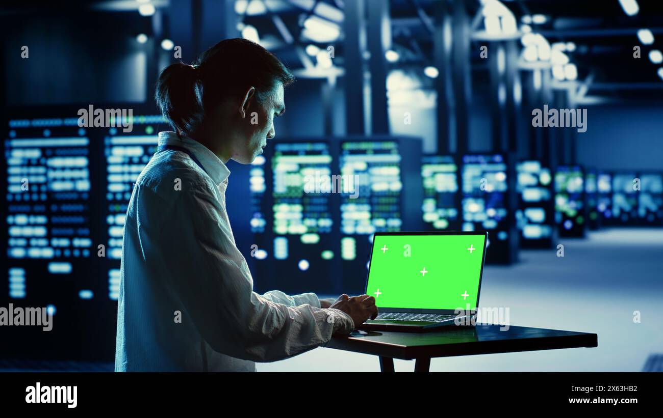 IT-Berater, der Code auf Chroma Key-Laptop ausführt, Fehlerbehebung bei Rechenzentrumsgeräten. Cloud-Computing-Manager verwenden Green-Screen-Geräte, um Server und Netzwerksysteme zu untersuchen Stockfoto