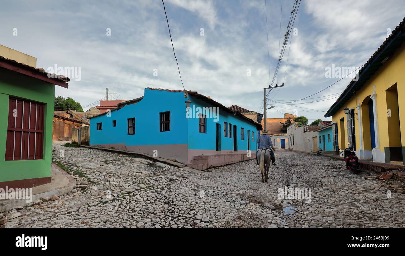 273 Reiter reiten neben einem Haus mit blauer Mauern auf rosa bemalten Sockel, Calle Amargura Street und Callejon de la Soledad Alley Ecke. Trinidad-Kuba. Stockfoto