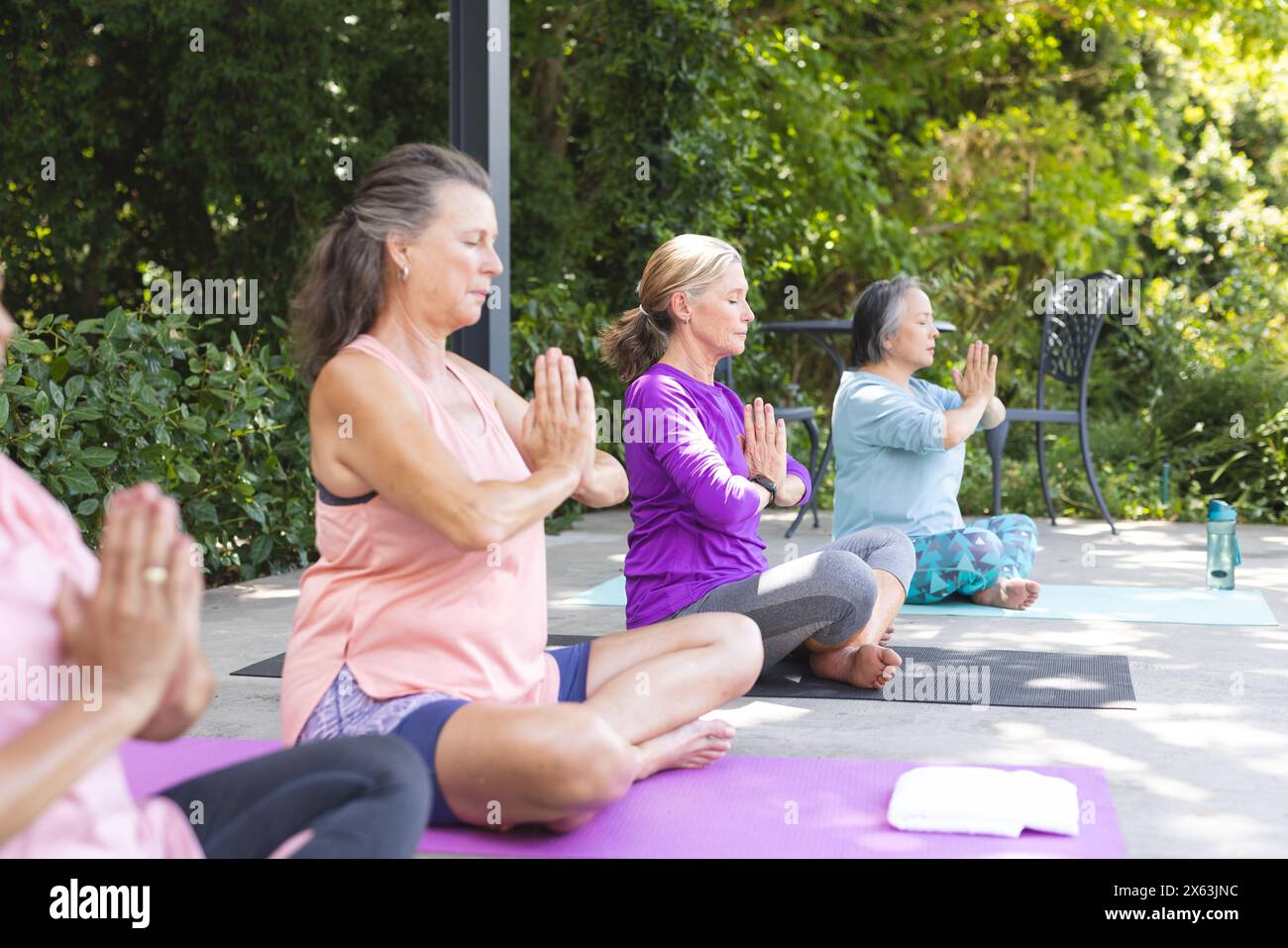 Im Freien, verschiedene ältere weibliche Freunde üben Yoga und konzentrieren sich auf Posen Stockfoto