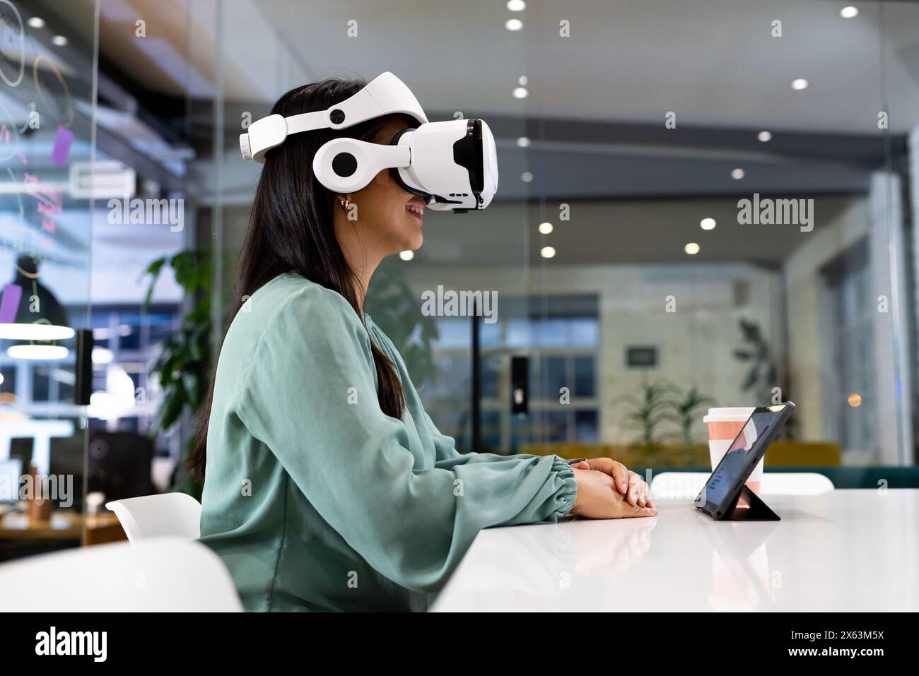 Im Büro sitzt eine Geschäftsfrau mit VR-Headset am Schreibtisch Stockfoto