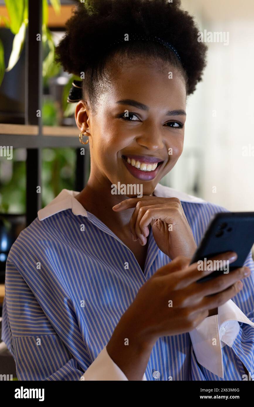 Afroamerikanische Geschäftsfrau lächelt, hält Telefon, arbeitet spät Stockfoto