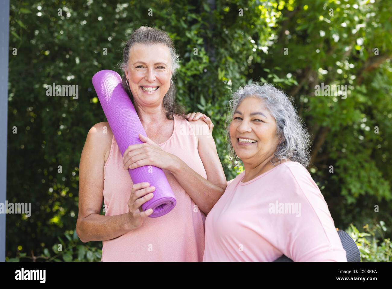 Draußen genießen, verschiedene ältere Freundinnen mit Yogamatten halten, beide lächeln Stockfoto