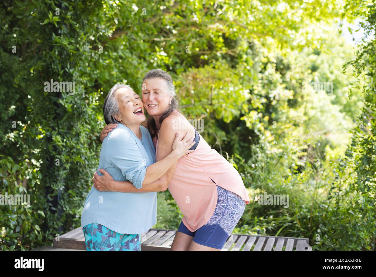 Draußen, verschiedene ältere Freundinnen, Asiaten und Kaukasier, umarmt Stockfoto