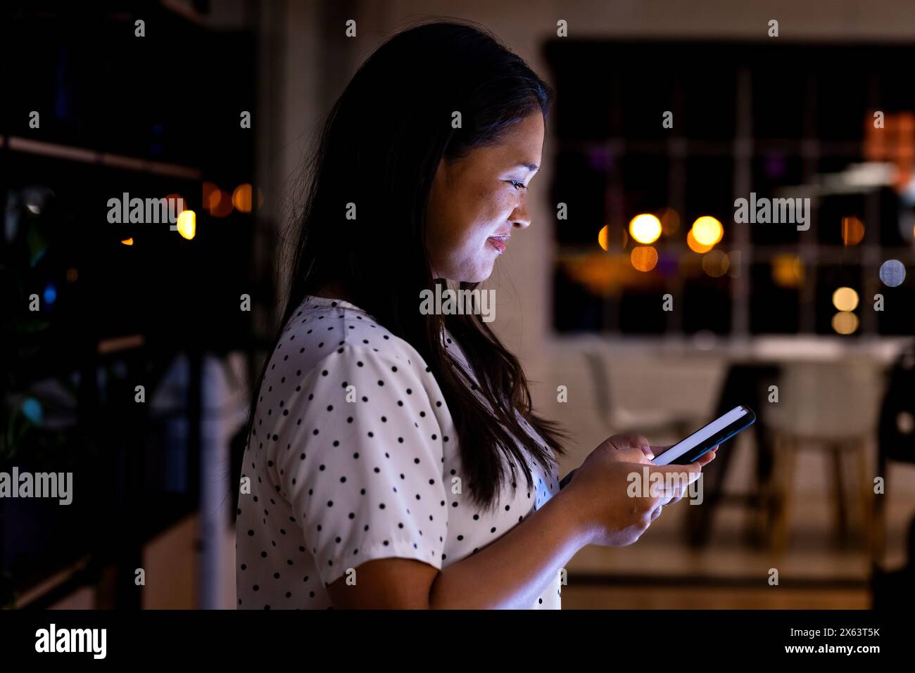 Im Büro, Geschäftsfrau mit birassischem Smartphone, die bis spät arbeitet Stockfoto