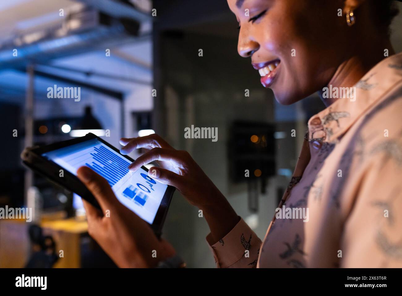 Afroamerikanische Geschäftsfrau überprüft Daten auf Tablet im Büro und arbeitet bis spät Stockfoto