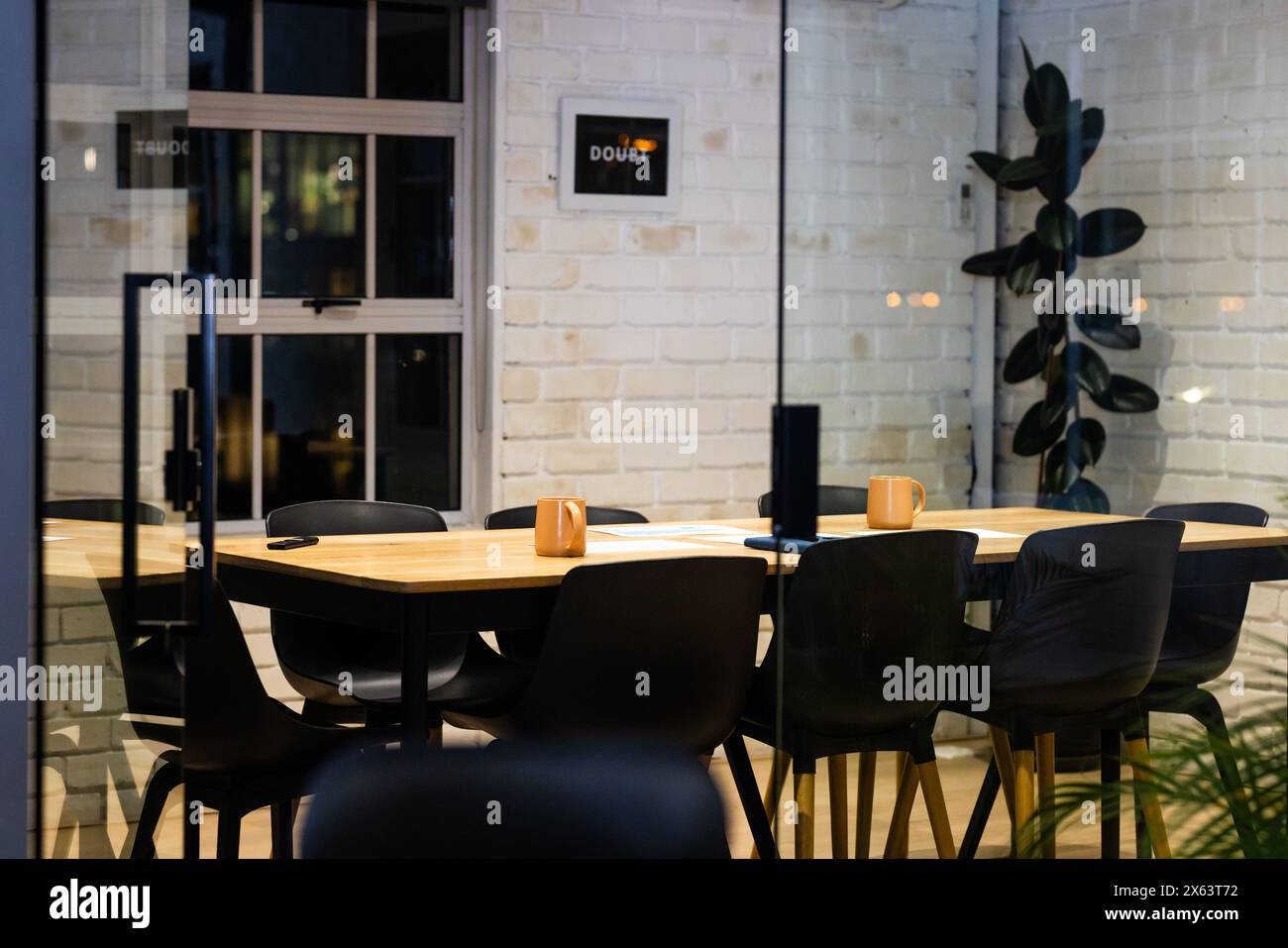 Im Büro, bis spät arbeiten, schwarze Stühle um den Holztisch Stockfoto