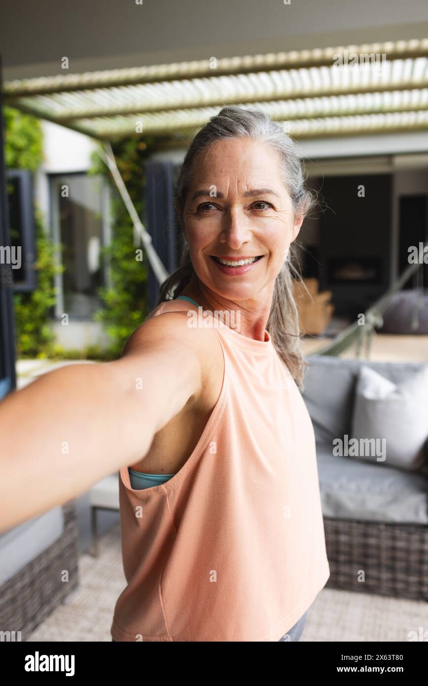 Zu Hause, reife Kaukasierin, die legere Kleidung trägt und Yoga macht Stockfoto