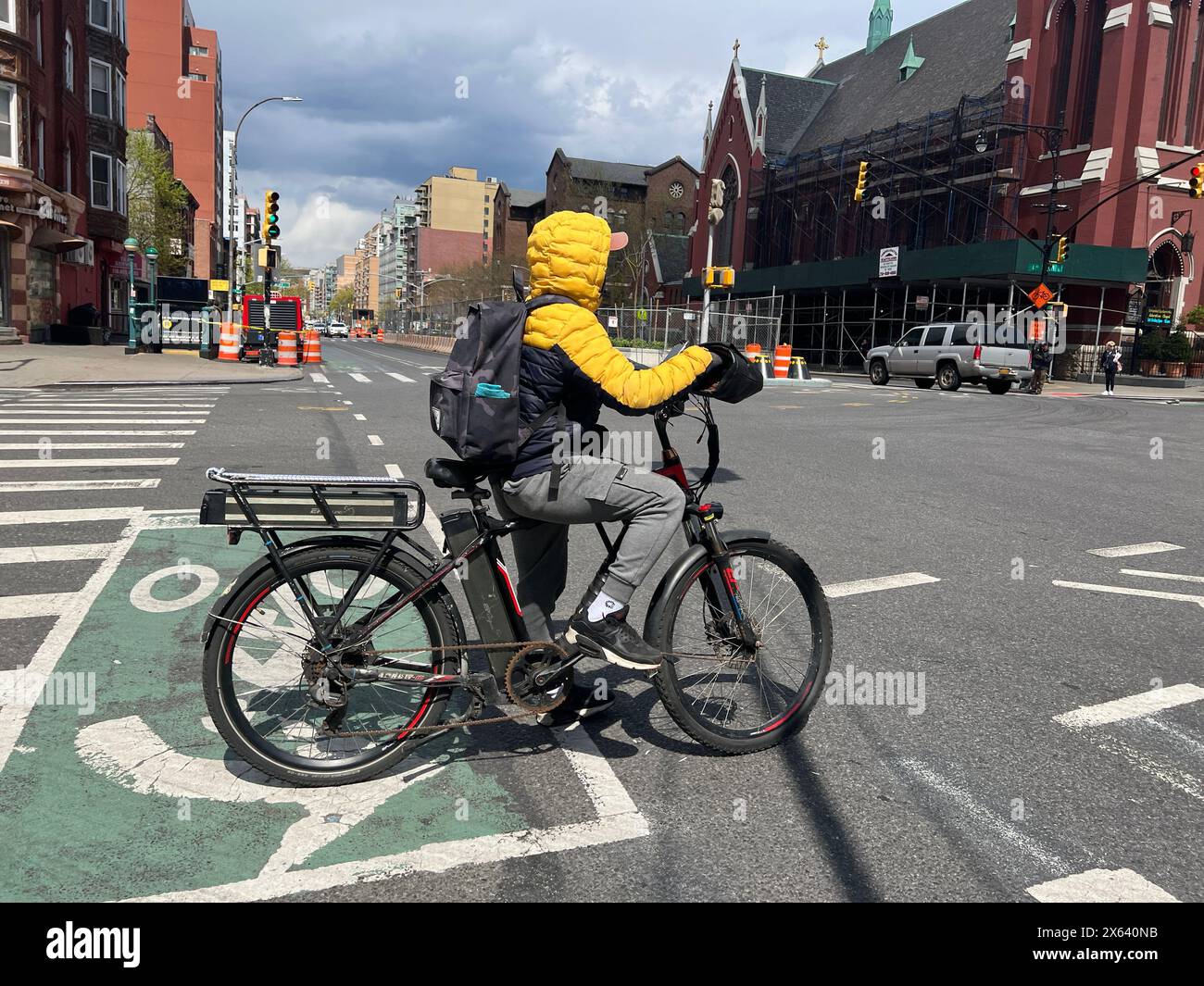 E-Bike-Fahrer-Lieferer warten auf die Ampel, die an der 4th Avenue und 9th Street im Park Slope Abschnitt von Brooklyn, New York, grün wird. Stockfoto