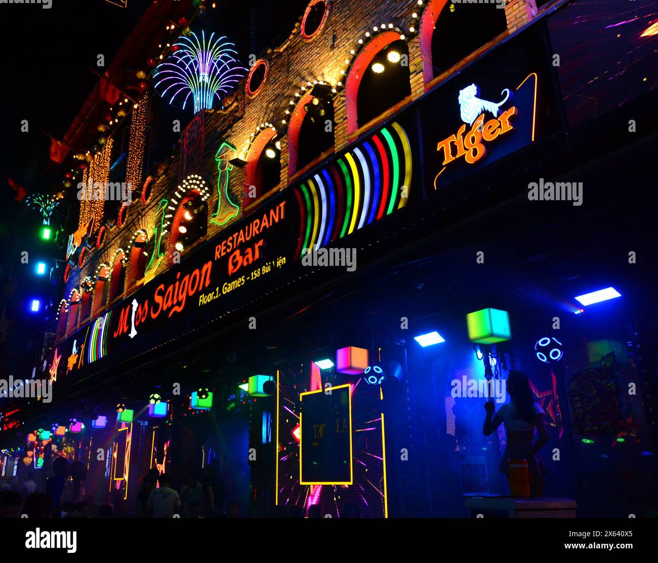 Das tägliche Leben in Ho-Chi-Minh-Stadt, die früher Saigon hieß, in Vietnam, Asien. Nachtleben auf der Walking Street Saigon, auch Bui Vien Street genannt, die Hauptstraße der sogenannten „Backpacker Gegend“ von Ho Chi Minh City. Eine Frau tanzt auf einem Tisch vor der Miss Saigon Bar, um Kunden anzulocken und zu unterhalten. Stockfoto