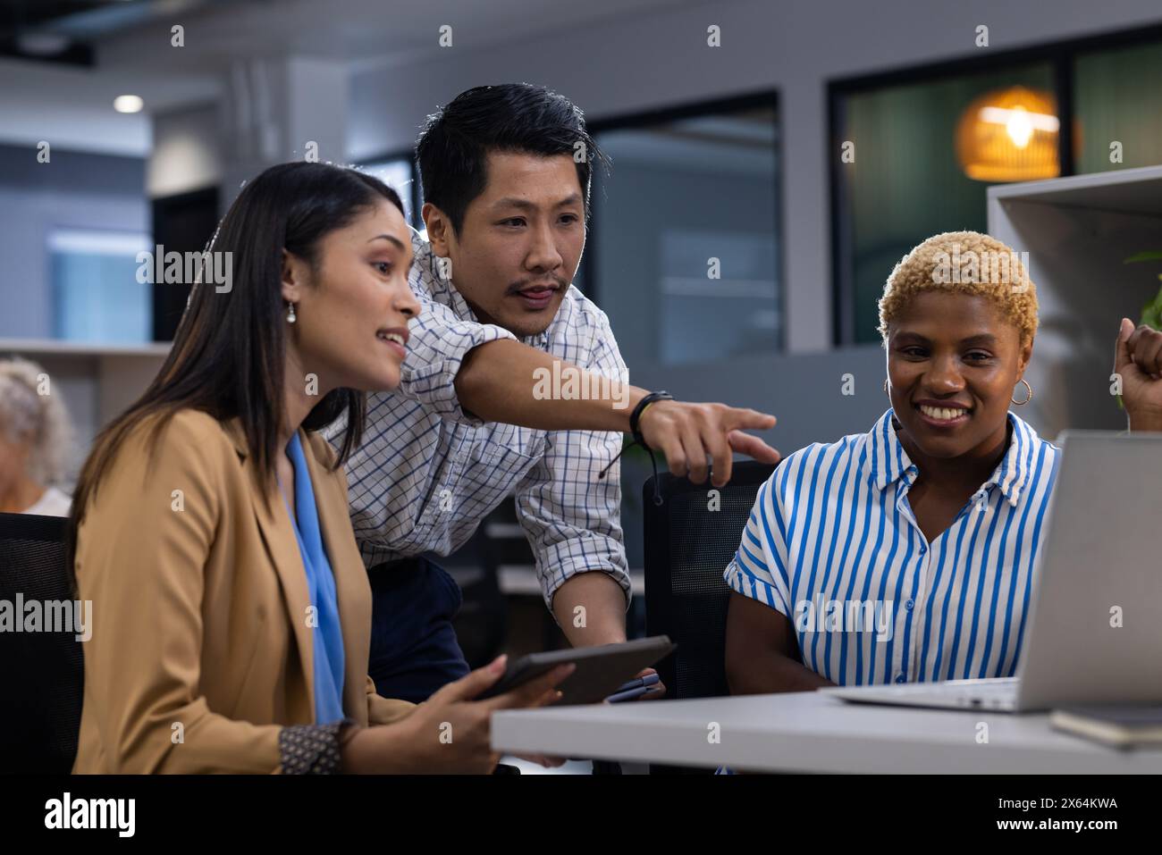 Büroszene mit vielseitigem Team: Asiatischer Mann, Afroamerikanerin, Bildschirm Stockfoto