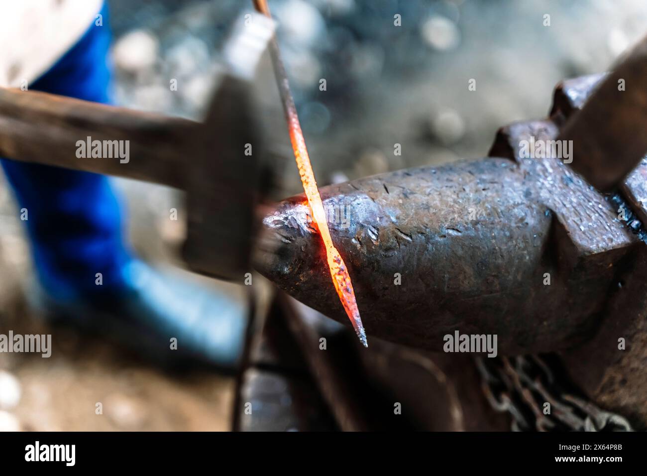 Ein Schmied in einer Schmiede arbeitet an einem Amboss. Heißmetallschmieden. Hochwertige Fotos Stockfoto