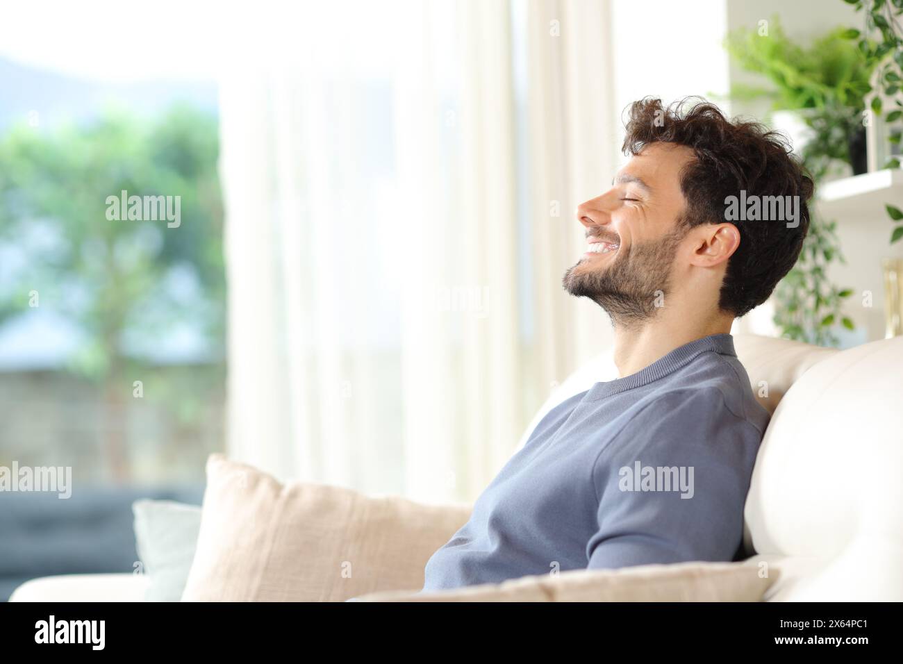 Seitenporträt eines glücklichen Mannes, der auf der Couch atmet und wieder aufnimmt Stockfoto