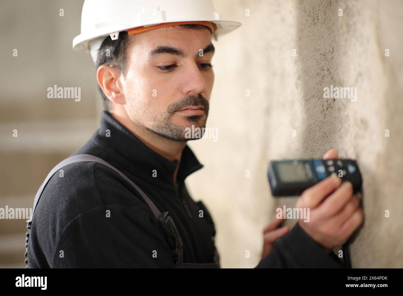 Bauarbeiter mit einem digitalen Entfernungsmesser in einer Wand Stockfoto