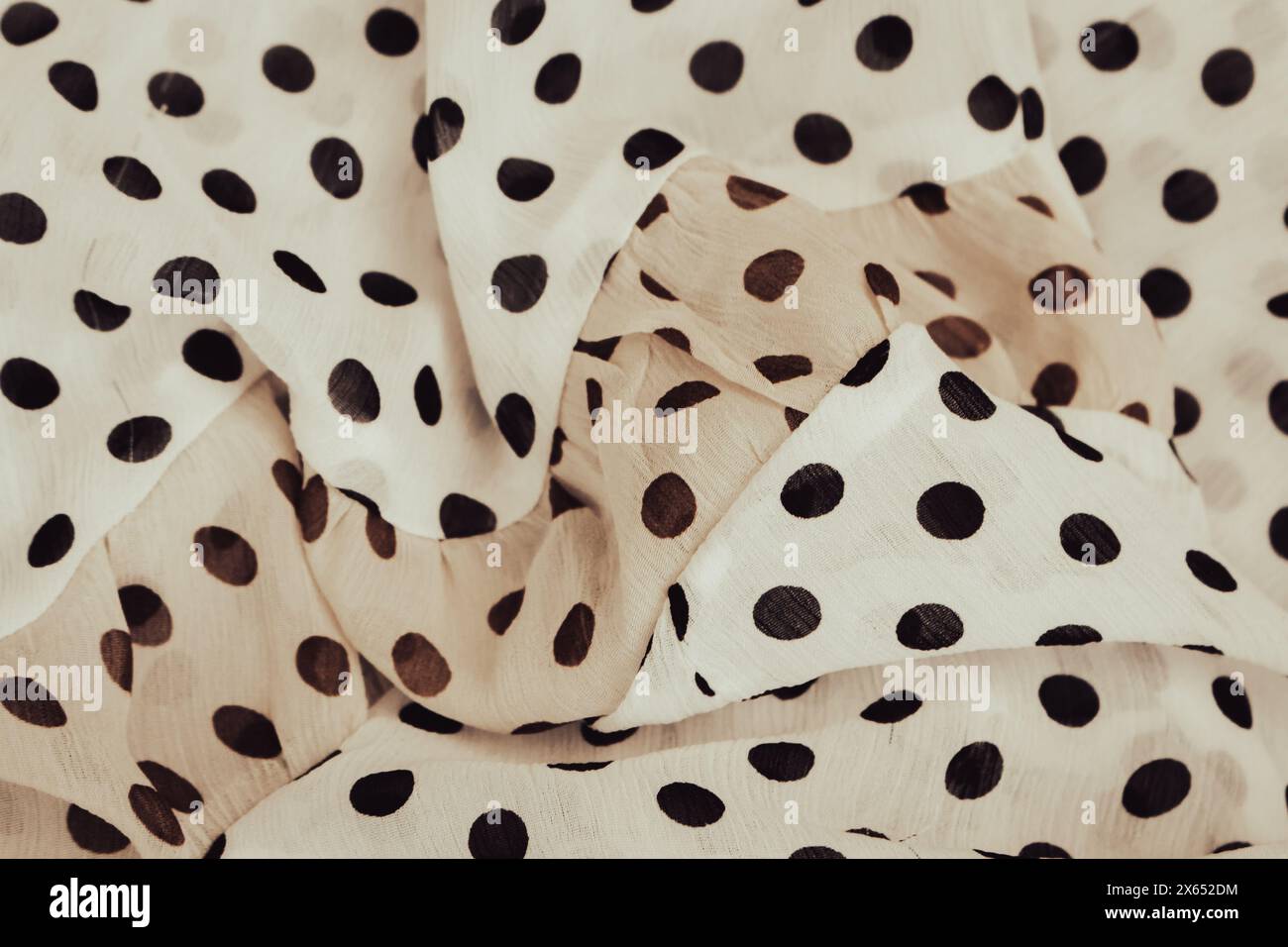 Hintergrund aus Stoff mit Punktmuster. Beigefarbenes gepunktetes Textilmuster. Falten Sie Chiffon-Gewebe. Hintergrund aus satiniertem Falten. Hintergrund aus Seidenstoff. Elegante Dekoration. Stockfoto
