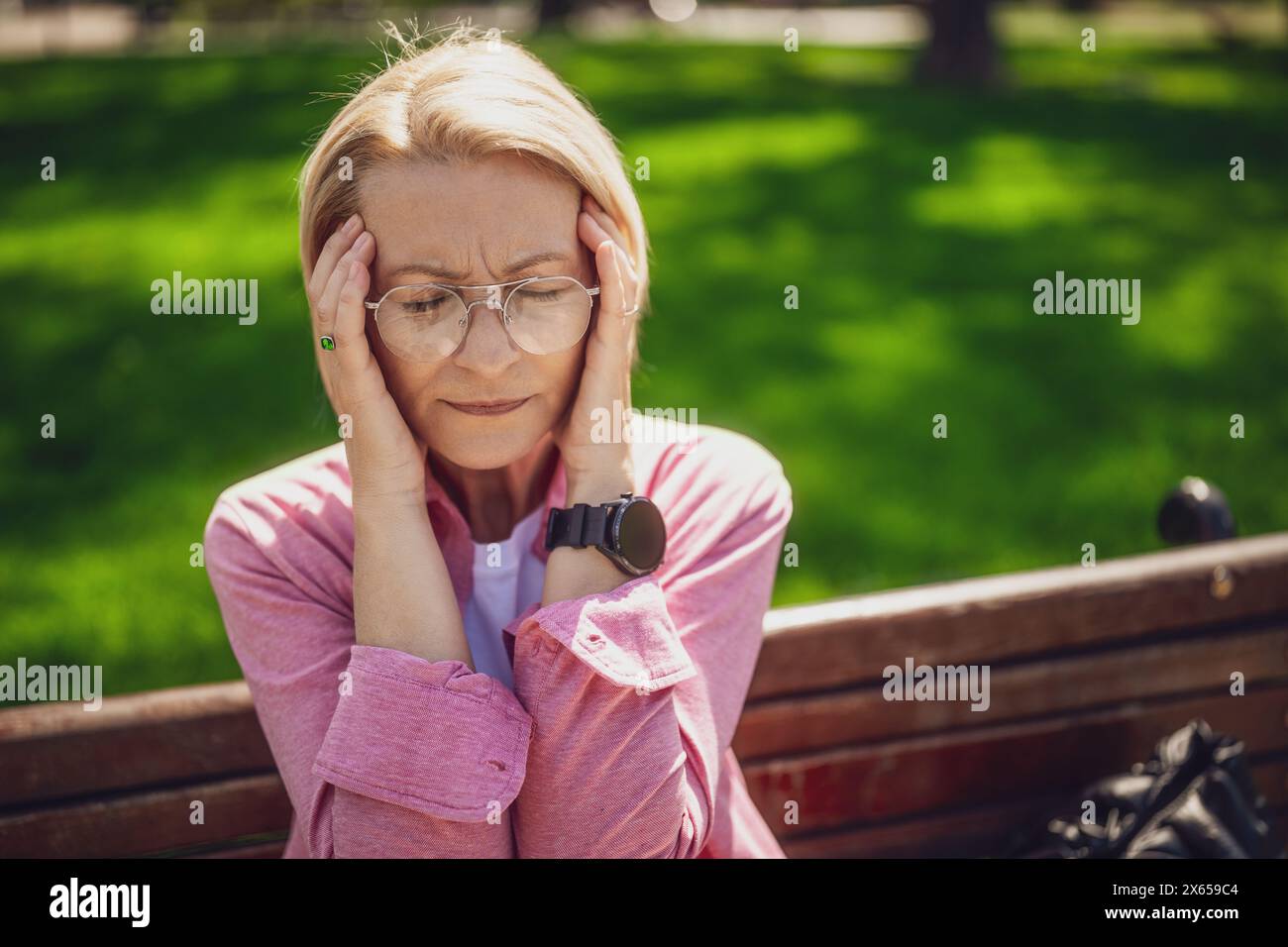 Porträt der Reifen Frau im Park. Sie hat Kopfschmerzen. Stockfoto