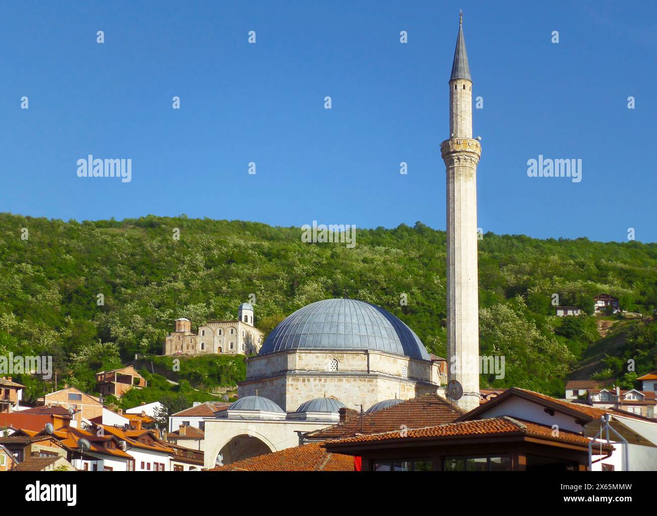 Minarett der Sinan-Pascha-Moschee mit der Kirche des Heiligen Erlösers im Hintergrund Hügel, Stadt Prizren, Kosovo Stockfoto