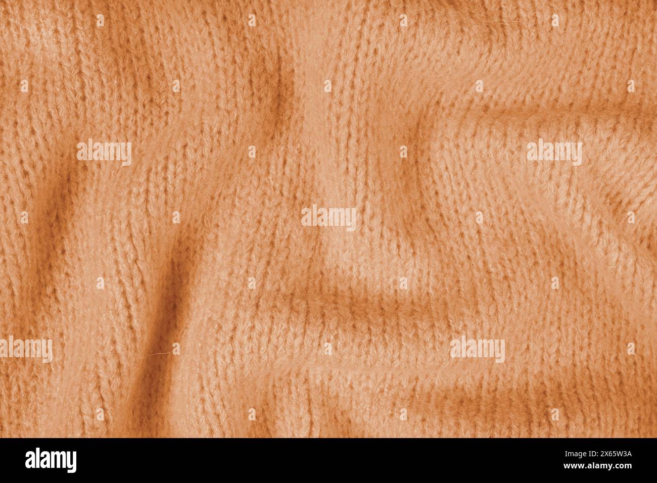 Nahaufnahme des Hintergrunds aus orangefarbenem Strickgewebe aus Viskosegarn. Zerknitterte Strickwolle, weicher Texturhintergrund. Abstrakt gestricktes Faltenmuster Stockfoto