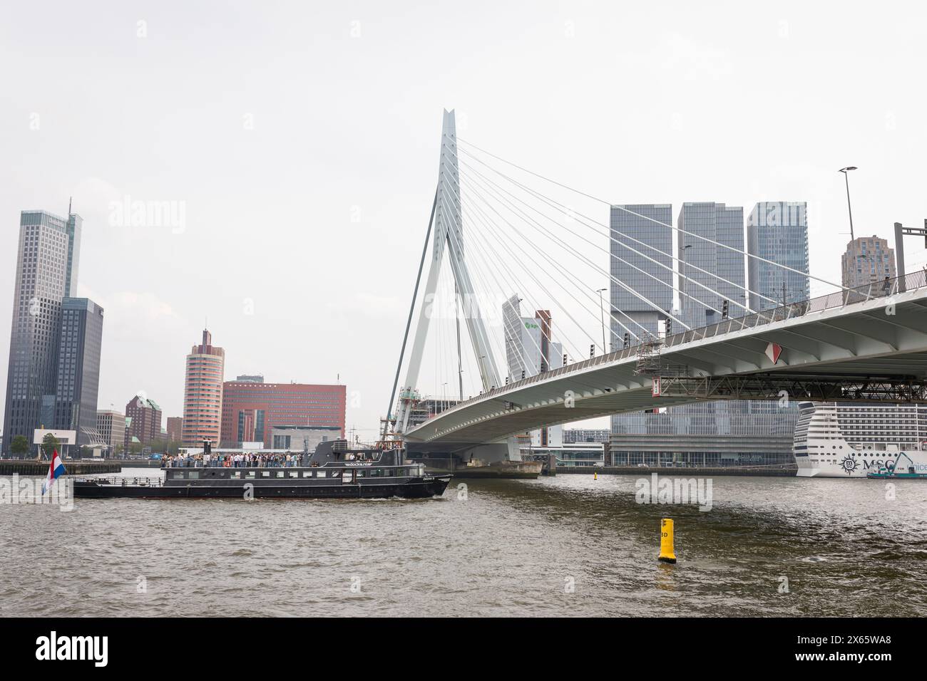 Partyboot mit Partygästen auf dem Oberdeck auf der Maas in Rotterdam, vorbei an der Erasmus-Brücke. Stockfoto