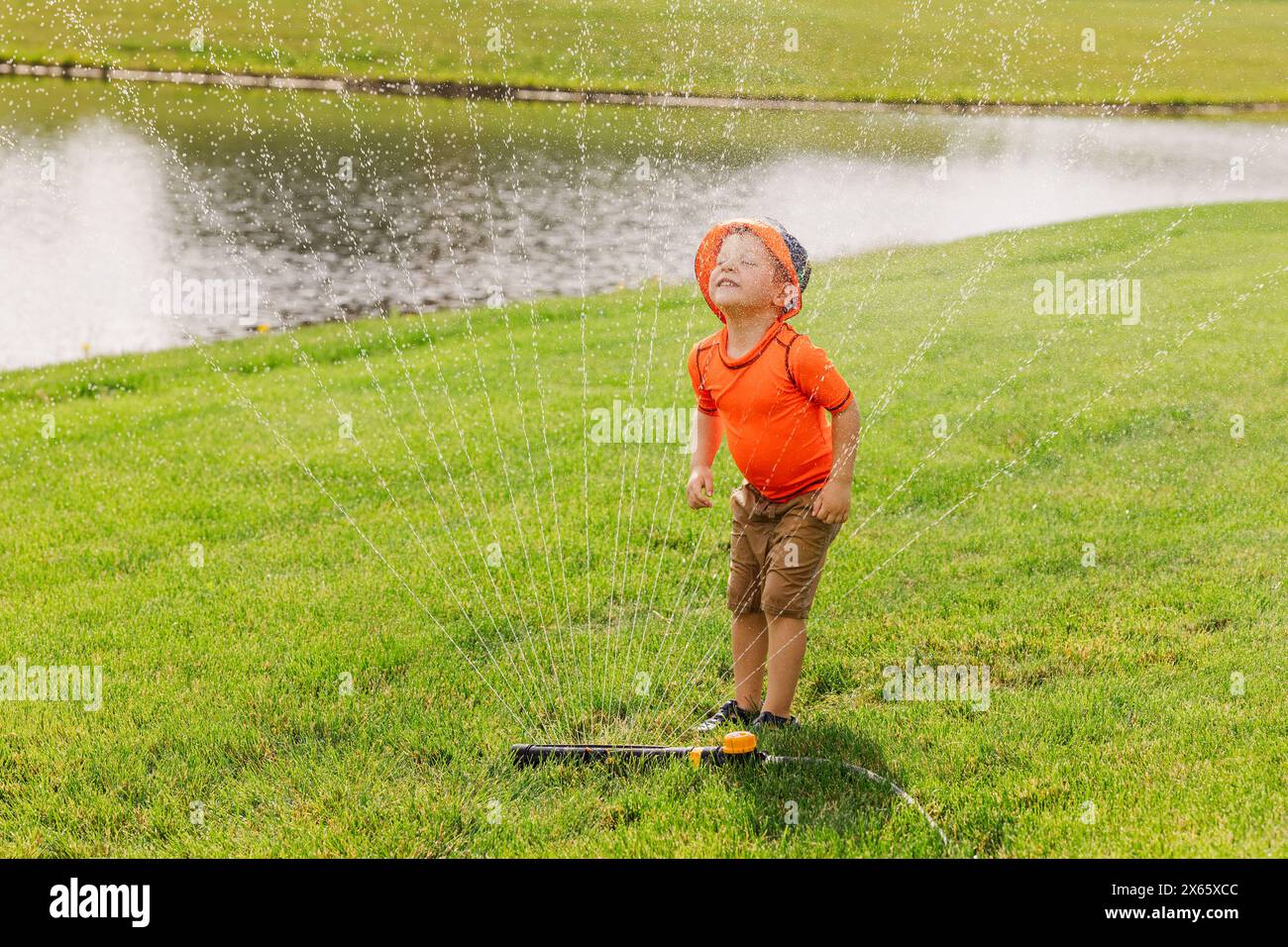 Kleines Kind genießt Wasserspiel im Rasen Stockfoto