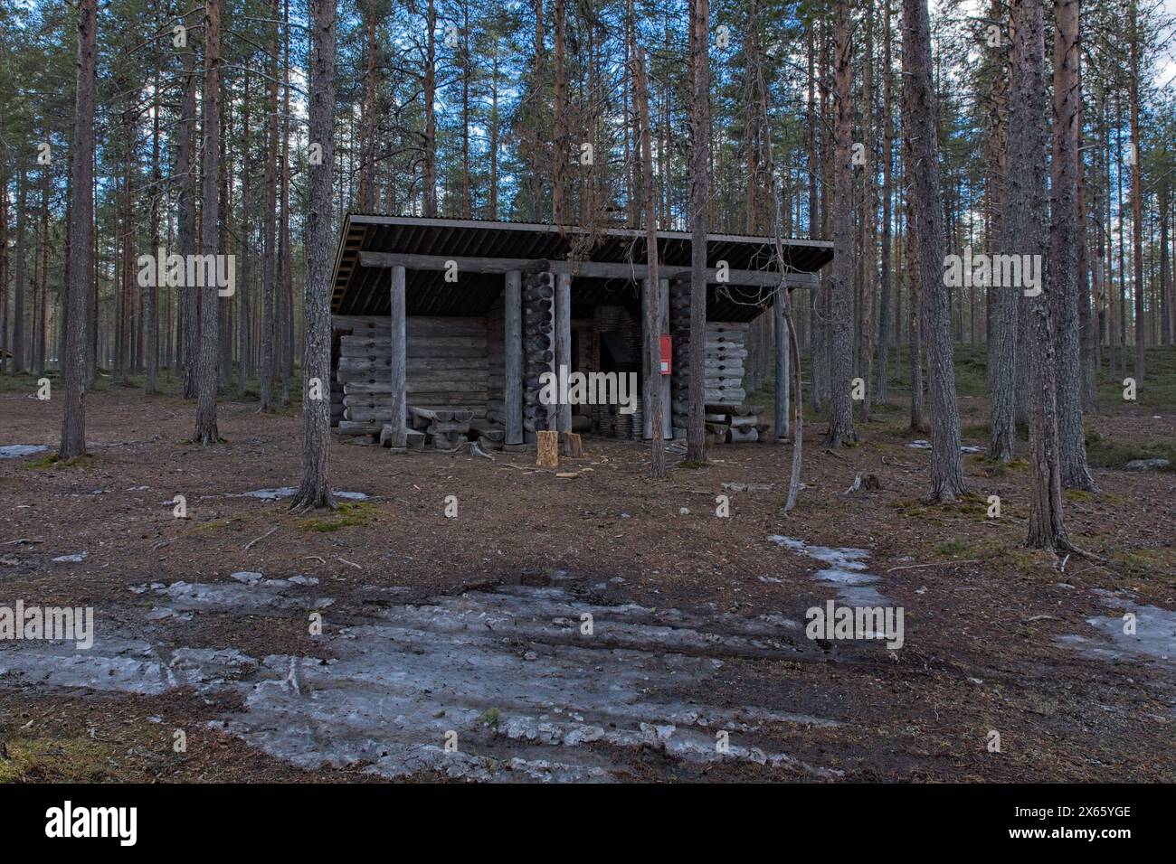 Campingunterkunft mit Lagerfeuer in der Nähe des Seeufers bei bewölktem Frühlingswetter, Iikoski, Hossa Nationalpark, Suomussalmi, Finnland. Stockfoto