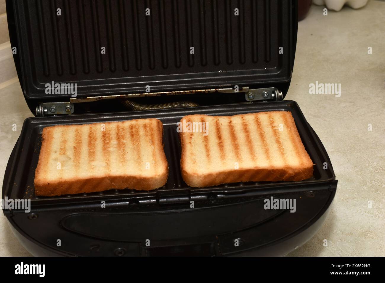 Das Bild zeigt einen elektrischen Grill mit getoastetem Toast für die Zubereitung von Sandwiches. Stockfoto