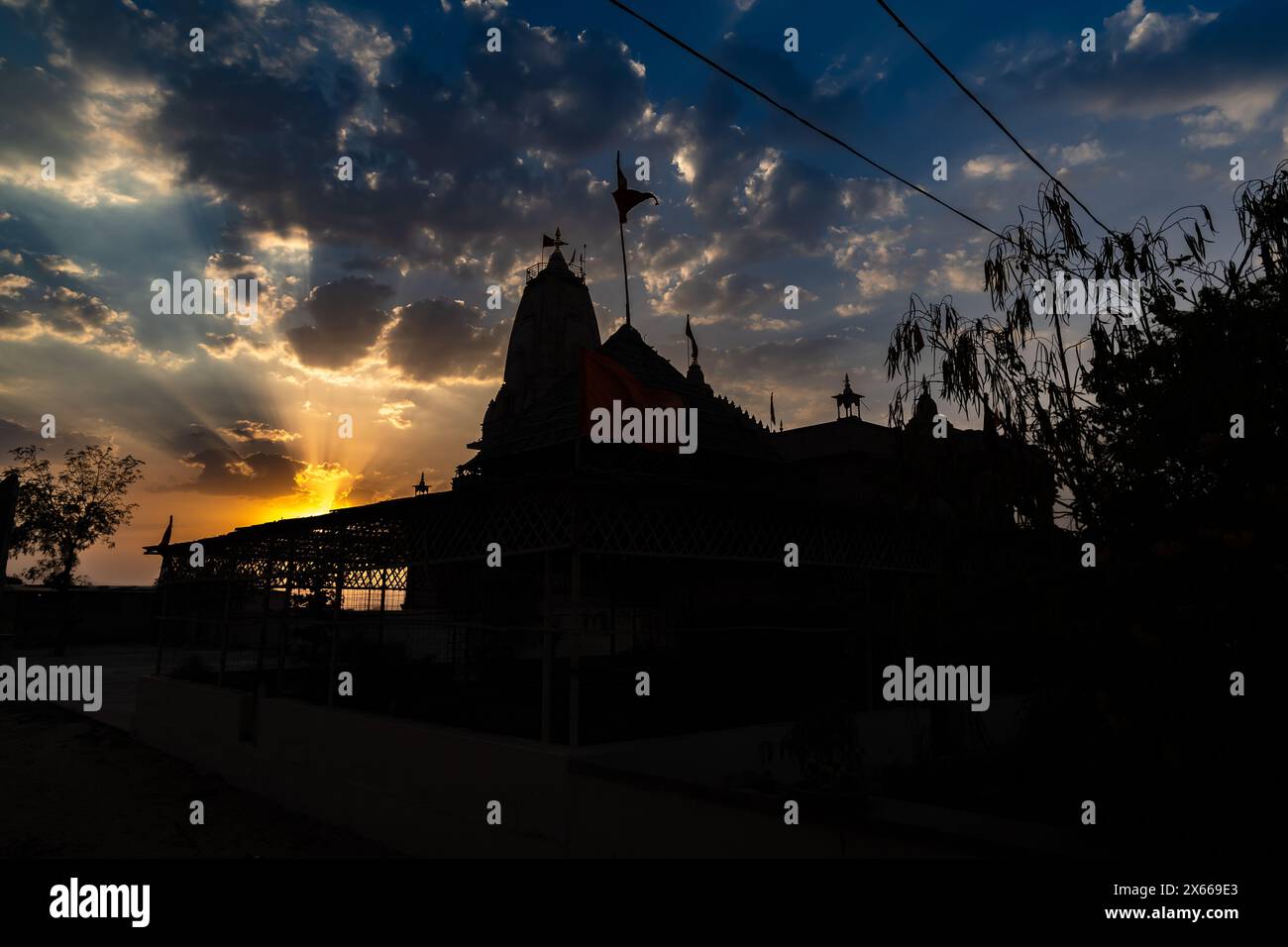 Hintergrundbeleuchtete Aufnahme des dramatischen Sonnenuntergangs und des künstlerischen hindutempels am Abend aus einer einzigartigen Perspektive Stockfoto