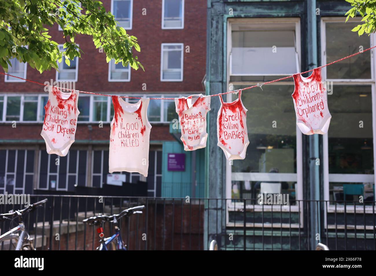 Rot gefärbte T-Shirts mit Blutflecken hängen in der Nähe der Universität Manchester, um gegen ihre angebliche Unterstützung Israels im anhaltenden Konflikt gegen Hammas in Gaza zu protestieren, wie sie am Montag, den 13. Mai 2024 in Manchester, England, zu sehen sind (Foto: MI News) Credit: MI News & Sport /Alamy Live News Stockfoto