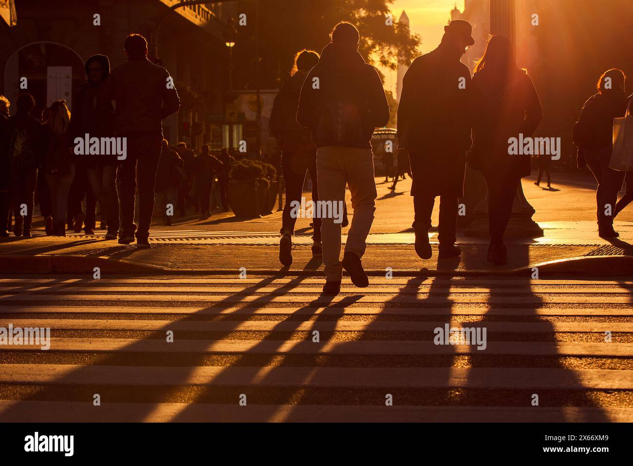 Menschen überqueren die Straße nach Diagonal Norte bei Sonnenuntergang mit dem Obelisken im Hintergrund, Plaza de Mayo, Buenos Aires, Argentinien. Stockfoto