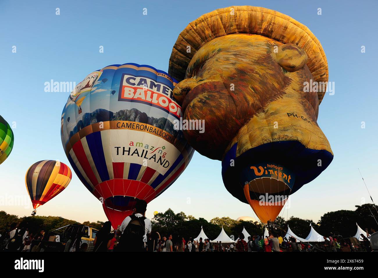 Eine Gruppe von Heißluftballons fliegt am Himmel, von denen einer wie das Gesicht eines Mannes geformt ist. Luftspektakel bei einem Festival mit mehreren Heißluftbällen Stockfoto