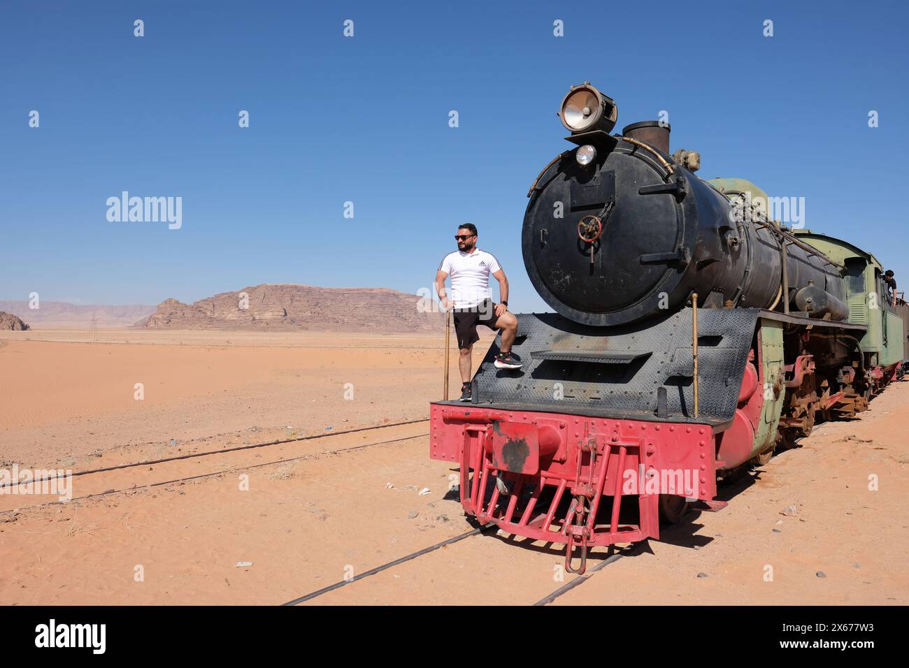 Hejaz, Wadi Rum, Jordanien – Besucher stehen auf einer Dampflokomotive ( Nippon 4-6-2 ), die von der Jordan Hedjaz Railway in der abgelegenen Wüste bei Wadi Rum betrieben wird Stockfoto