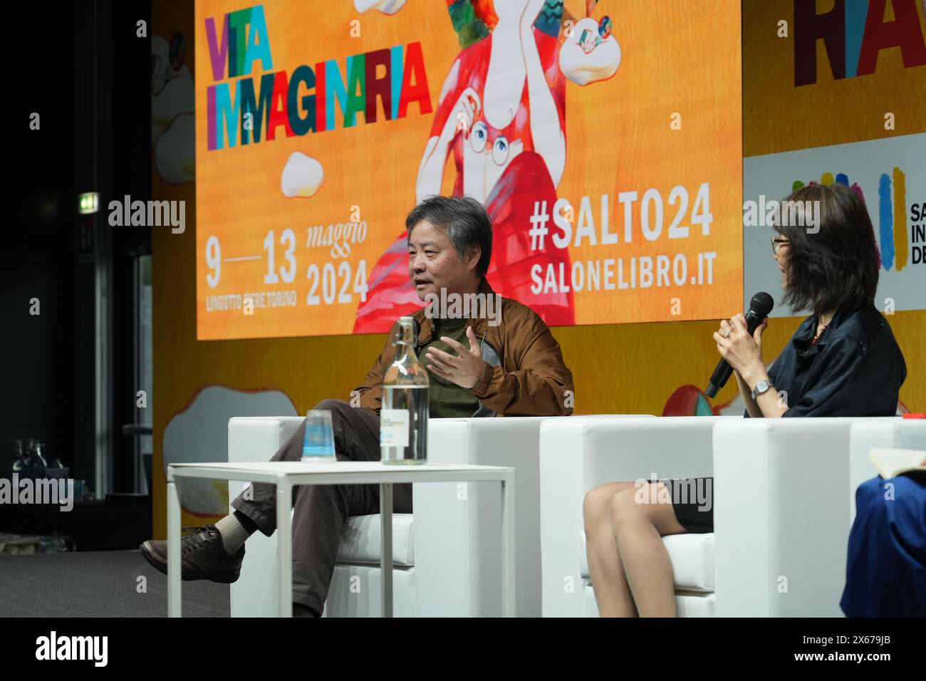 Turin, Italien. Mai 2024. Der chinesische Schriftsteller Yu Hua (L) spricht bei einer Unterschriftensitzung auf der Internationalen Buchmesse in Turin, Italien, 12. Mai 2024. ZU „Chinesische Bücher erregen weltweite Aufmerksamkeit auf Italiens größter Buchmesse“ Credit: Ren Yaoting/Xinhua/Alamy Live News Stockfoto