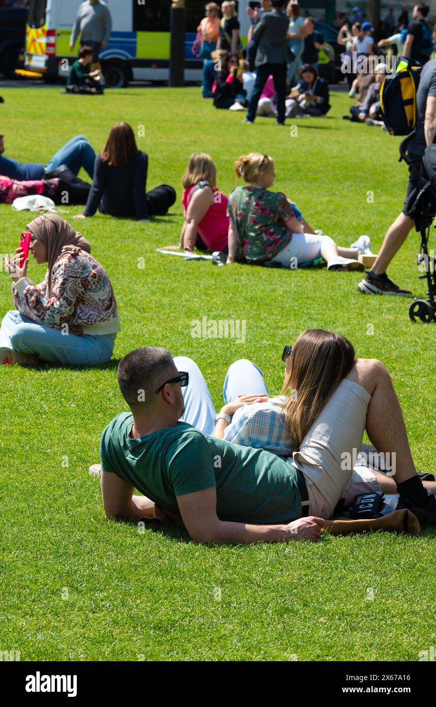 Die Menschen genießen die warme Sonne am Parliament Square, London. Stockfoto