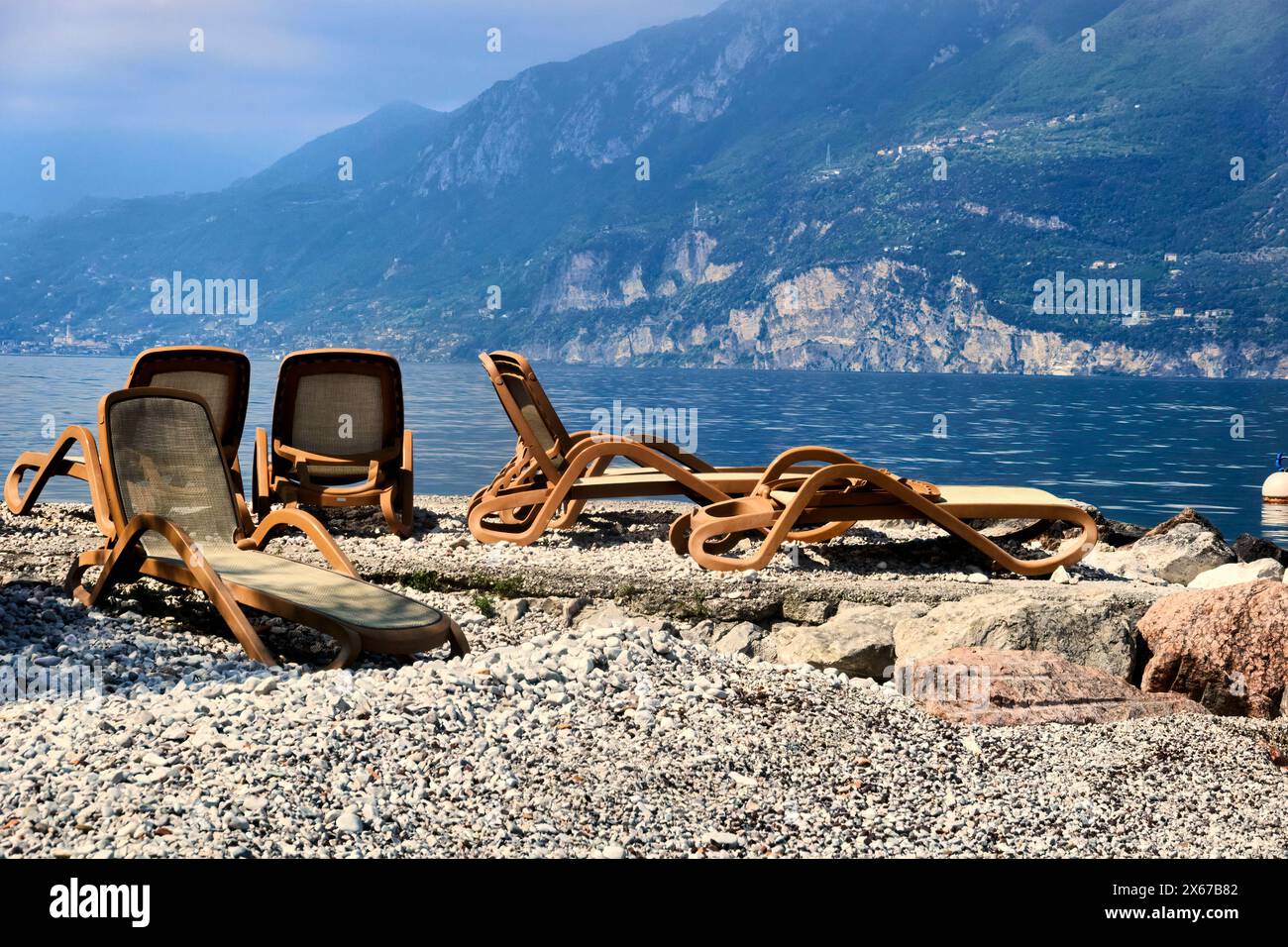 Leere Liegestühle vor Beginn der Weihnachtszeit an einem Kieselstrand am Gardasee in Italien Stockfoto