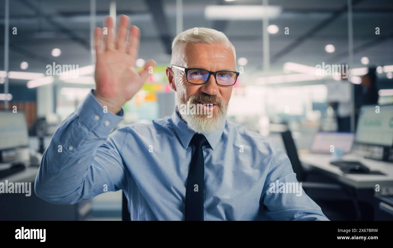 Porträt eines gutaussehenden erfahrenen Senior Managers, der einem Kunden bei Videoanrufen in Modern Office zuwinkt. Geschäftskonferenz mit Partnern, Kollegen, Familienmitgliedern oder Freunden am Computer. POV-Ansicht. Stockfoto